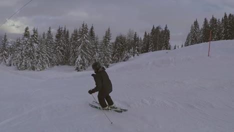 Slow-motion-shot-of-a-male-enjoying-riding-on-skis-fast-downhill-right-under-the-ski-lift-on-the-slope