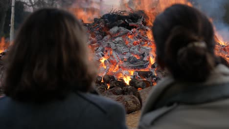 Zwei-Frauen-Betrachten-Großes-Lagerfeuer,-Um-Die-Weihnachtszeit-Zu-Feiern,-Portugal