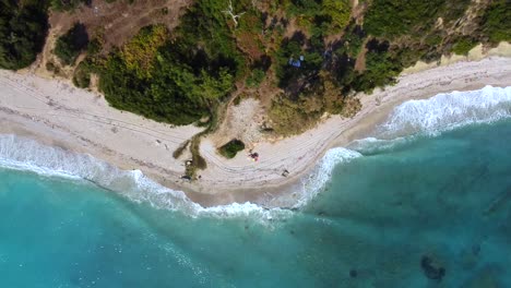 Drone-shot-of-an-Albanian-beach---drone-is-descending-in-birds-eye-view-towards-a-parasol