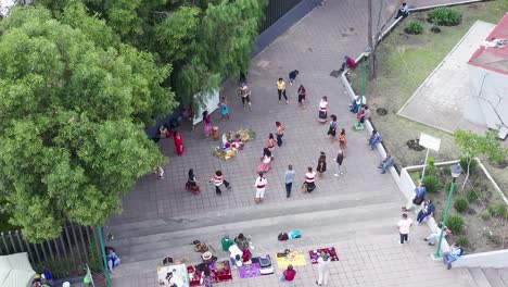 Many-Yaki-native-people-dancing-danza-del-venado-traditional-authentic-dance-in-downtown-city-park,-jumping,-kicking,-hopping,-spinning-and-in-circle,-Mexico-city,-overhead-aerial