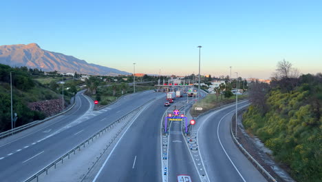 Top-view-of-a-toll-road-in-Marbella-Malaga-Spain-with-the-beautiful-La-Concha-mountain,-cars-driving-on-the-highway,-4K-shot