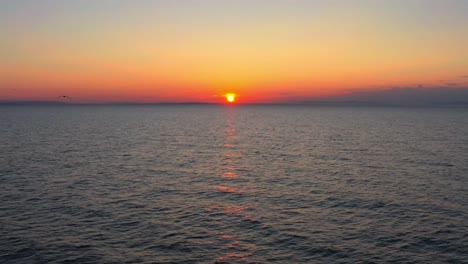 Maravilloso-Atardecer-Drone-En-El-Mar,-Gaviotas-Volando-Contra-El-Sol,-Plataforma-Rodante-Aérea