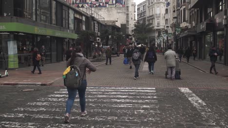 People-crossing-Sarandi-Street-and-Plaza-Independencia,-Montevideo