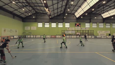 Los-Niños-Que-Juegan-Hockey-Sobre-Patines-En-Un-Centro-Deportivo-Generan-Una-Jugada-De-Ataque-Rápida-Y-Agresiva-Con-Tiro-Al-Portero-Rival,-Tiro-De-Seguimiento.