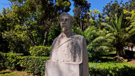 Old-statue-of-person-in-tropical-park-of-Athens-city,-motion-view