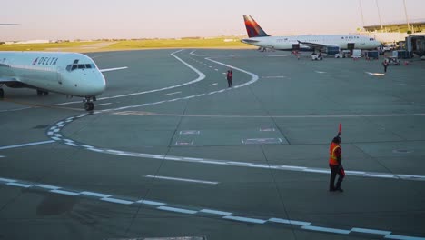 Delta-Flugzeug-Dockt-Tagsüber-Mit-Einweisern-An-Einem-Flughafen-An,-Flug,-Flugzeug,-Dock,-Reise,-Fluggesellschaft