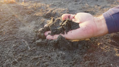 Hand-Erkundet-Den-Einzigartigen-Schwarzen-Sand-Des-Strandes-Bibijagua-Bei-Sonnenaufgang