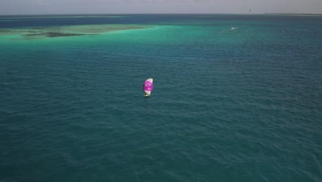 A-hydrofoil-surfer-on-vibrant-turquoise-waters-near-sardinia,-aerial-view