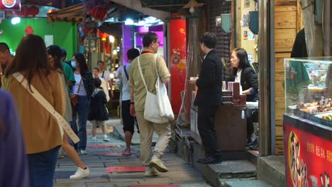 People-walking-the-narrow-laneway-of-Jiufen-Old-Street,-visiting-the-famous-Taiwan-mountain-village,-exploring-the-vibrant-food-stalls,-souvenir-shops,-and-eclectic-gift-boutiques