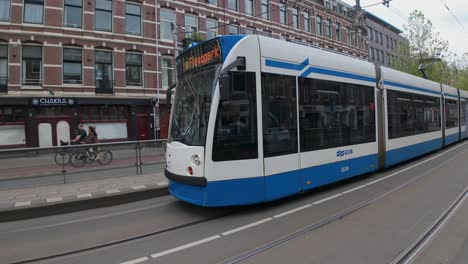 A-tram-and-bikers-on-the-street-in-Amsterdam,-Netherlands