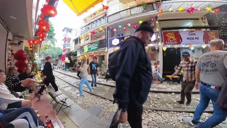 People-moving-along-Hanoi-Train-Street,-a-narrow-train-bypass-,-in-a-timelapse-that-show-on-both-sides-of-the-tracks