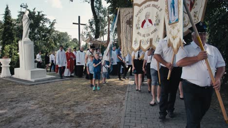 Procession,-with-believers-with-banners-going-around-a-church-in-the-countryside