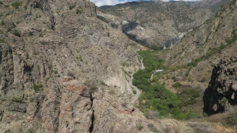 Paso-Elevado-De-Una-Cresta-De-Roca-Afilada-Para-Revelar-Un-Profundo-Desfiladero-De-Piedra-Con-Una-Carretera-Debajo