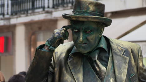 Man---Living-Statue-in-close-up,-his-body-and-clothes-in-copper-tones,-performing-for-people-passing-by-on-Rua-Augusta,-in-downtown-Lisbon