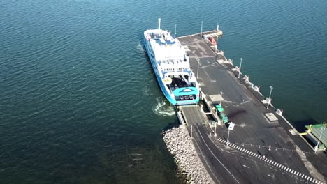 ascending-aerial-view-above-the-ferry-boat-docked-at-the-port-of-estonia-with-car-leaving-the-area