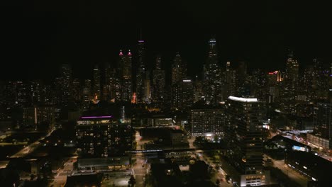 Aerial-view-overlooking-the-CTA-train-moving-through-the-nighttime-Near-North-Side-cityscape-of-Chicago,-USA