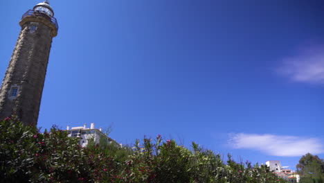 Old-stone-lighthouse-of-Estepona-against-blue-sky,-panning-view