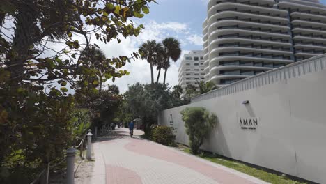 Camino-En-Miami-Beach-Bordeado-De-árboles-Y-Edificios-Modernos,-Con-Gente-Disfrutando-Del-Día-Soleado