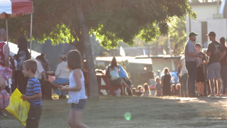 Familias-Con-Niños-Jugando-Caminan-Por-El-Recinto-Ferial-En-Una-Tarde-De-Verano