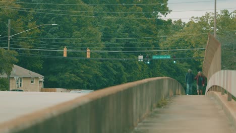 Two-Men-Walk-Across-A-Bridge-As-Traffic-Passes-By