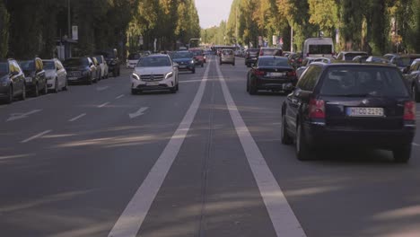 Munich,-Germany-–-October-20,-2019:-Traffic-drives-along-a-tree-lined-residential-street-in-Munich,-Germany