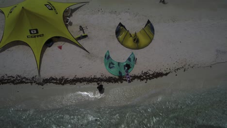 People-preparing-kites-on-a-sandy-beach,-aerial-view