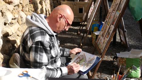 Un-Artista-Portugués-Masculino-Haciendo-Pintura-Al-Agua-Al-Aire-Libre-En-La-Calle.