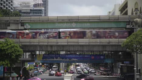 BTS-Skytrain-Conduciendo-Por-Una-Calle-Muy-Transitada-En-El-Centro-De-La-Ciudad,-Bangkok