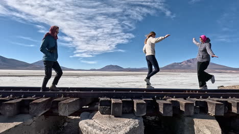 Friends-balance-and-play-as-they-walk-across-timber-tracks-of-railroad