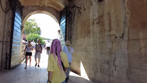 Back-view-of-a-young-woman-traveler-walking-across-the-historic-old-town-of-Dubrovnik,-Croatia,-capturing-the-spirit-of-adventure-and-cultural-exploration