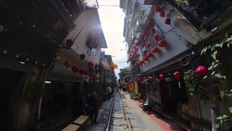 Ein-Zweimal-Täglich-Verkehrender-Zug-Fährt-In-Der-Nähe-Von-Gebäuden-Auf-Beiden-Seiten-Der-Gleise-Auf-Der-Hanoi-Train-Street-Vorbei,-Einer-Schmalen-Umgehungsstraße-