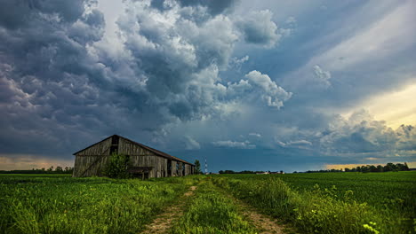 Dark-storm-clouds-form-above-an-old-dilapidated-barn-in-a-green-meadow