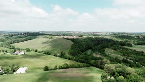 Vista-Aérea-De-Amplios-Campos-Verdes-Y-Zonas-Boscosas-Bajo-Un-Cielo-Azul-Cerca-De-Toulouse,-Francia