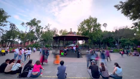 Timelapse-Panorámico-Tomado-Con-Una-Lente-Gran-Angular-Del-Quiosco-En-El-Centro-Histórico-De-Coyoacán-Al-Mediodía-De-Un-Sábado-Que-Muestra-A-Muchas-Personas-Caminando-Por-Los-Alrededores.