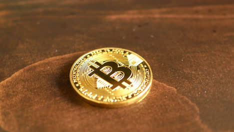 A-physical-golden-Bitcoin-rests-on-a-wood-table