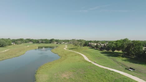 An-aerial-drone-view-of-a-woman-riding-a-bicycle-through-Exploration-Green-on-clear-sunny-day-in-Clear-Lake,-Houston,-Texas