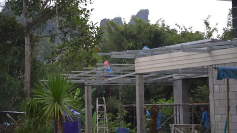 A-slow-motion-side-shot-of-Thai-men-welding-the-roof-beams-on-a-house-in-the-jungle