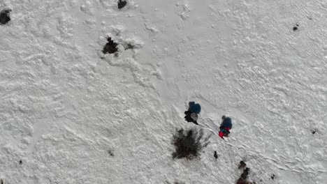 Two-travelers-trekkers-walking-hiking-through-a-snow-field