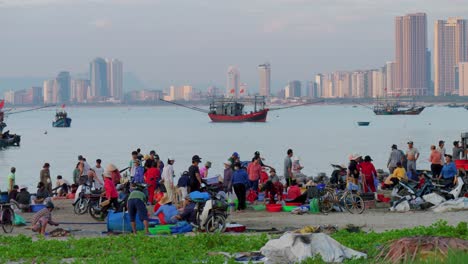 Gente-Local-Reunida-Con-Pescadores-Y-Familiares-Al-Atardecer-Con-Vista-De-Rascacielos-Del-Paisaje-Urbano-A-Distancia