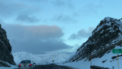 Eine-Malerische-Fahrt-Zwischen-Schneebedeckten-Bergen-Mit-Klarem-Himmel-Und-Einer-Eisigen-Brise