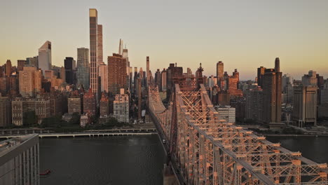 NYC-New-York-Aerial-v365-flyover-Roosevelt-Island-along-Queensboro-Bridge-capturing-traffics-crossing-and-sunrise-glow-over-cityscape-of-Midtown-Manhattan---Shot-with-Mavic-3-Pro-Cine---September-2023