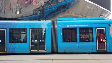 The-West-Midlands-Metro-light-rail-tram-system-traveling-past-Bullring-and-Grand-Central-train-station-in-the-county-of-West-Midlands,-Birmingham,-England-UK