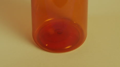 Slow-motion-high-angle-close-up-of-the-bottom-of-a-pill-bottle-as-a-single-pill-falls-in