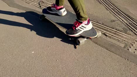 Low-angle-of-skateboarder-on-long-skateboard-riding-on-sidewalk,-sustainable