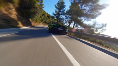 Antena-Panorámica-De-FPV-Siguiendo-Un-Lamborghini-Verde-Conduciendo-Por-Una-Carretera-De-Montaña-En-España