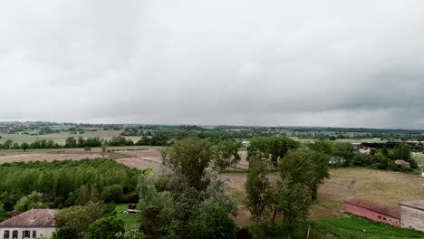 Luftaufnahme-Eines-Ländlichen-Dorfes,-Umgeben-Von-Feldern-Und-Bäumen-Unter-Einem-Wolkigen-Himmel-In-Der-Nähe-Von-Toulouse,-Frankreich