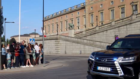 Coche-De-Policía-Encubierto-Negro-Con-Luces-Parpadeantes-Junto-Al-Palacio-Real-Sueco-En-El-Día-Nacional,-Slomo