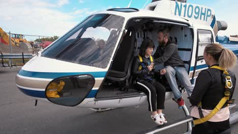 Two-women-looking-and-listening-to-an-instructor-showing-how-to-strap-in-before-a-helicopter-ride-over-Manhattan,-New-York-City