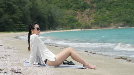 Woman-relaxing-on-sandy-beach-with-turquoise-water-and-lush-greenery-in-Con-Dao-Island-Vietnam