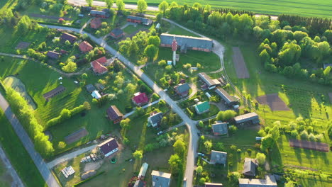 Malerische-Luftaufnahme-Eines-Kleinen-Dorfes-Mit-Goldenem-Sonnenlicht-Und-Langen-Schatten